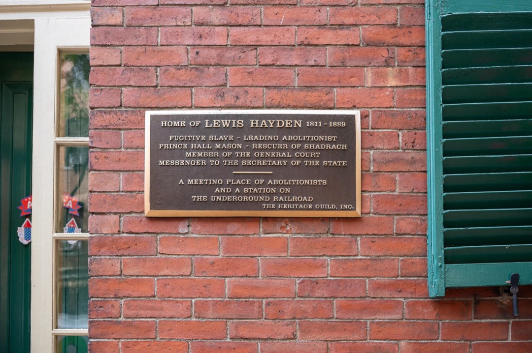 Close up of a plaque on the brick facade of the Hayden House, which has green shutters