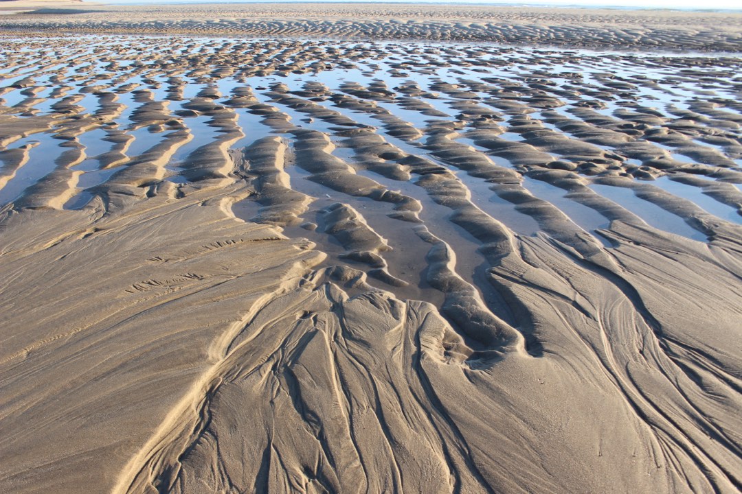 Low tide exposes rippled ridges of sand and water.