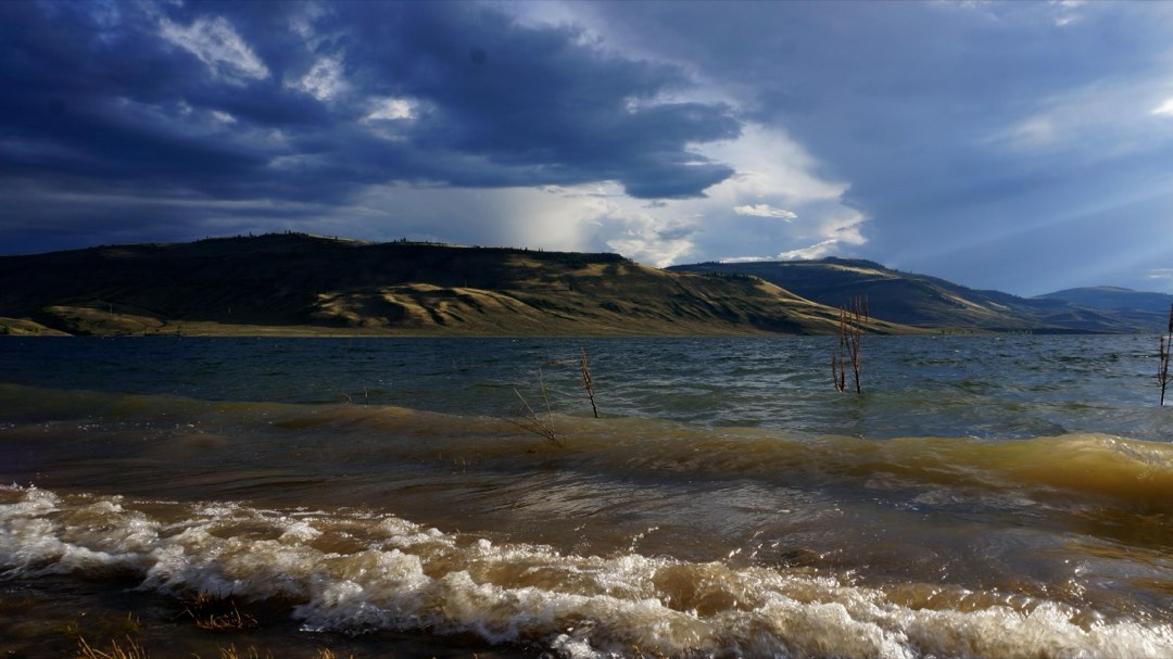 Underexposed shot of waves coming off a reservoir. Mesas in the background.