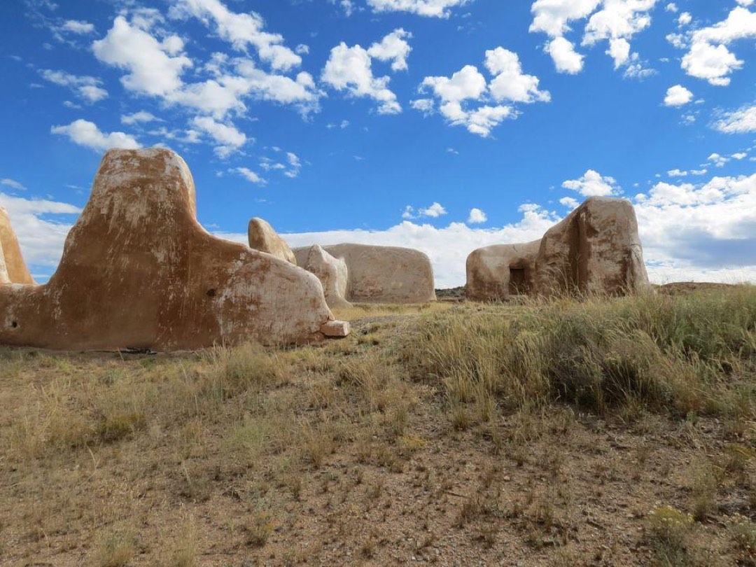 Ruins of adobe building under a blue sky with white clouds.