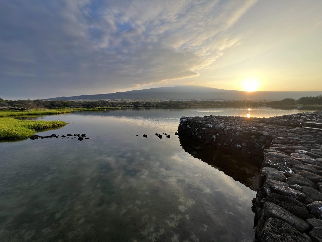 Sun rises over Hualālai volcano as seen from the Kaloko fishpond wall