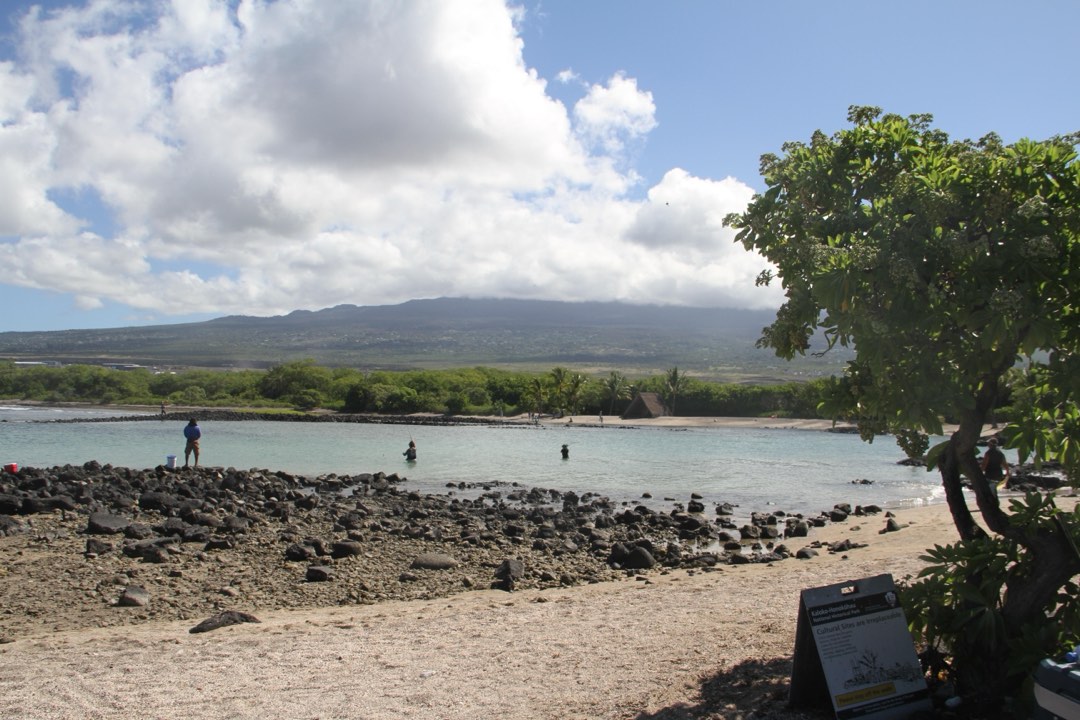 White sand beach at the base of a large volcano.