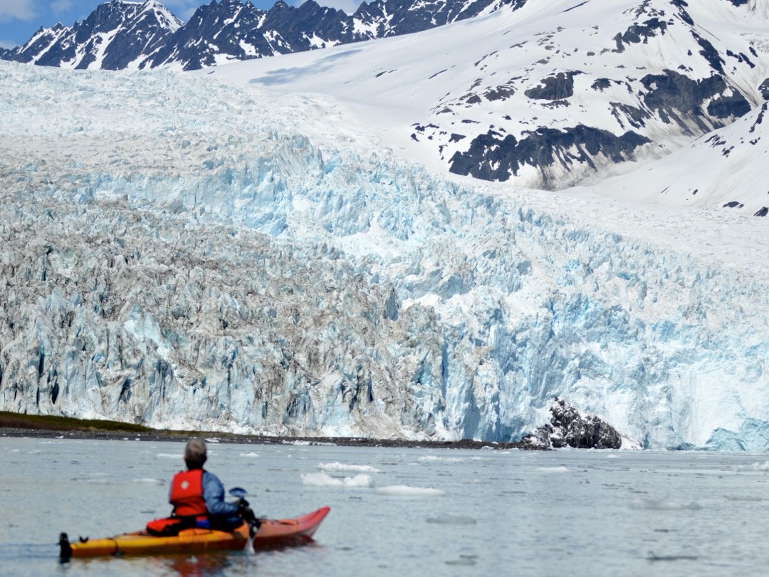A kayaker views a tidewater glacier in the distance