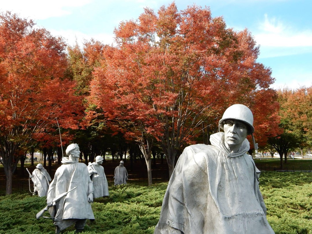 Statues of servicemen from the Korean War with fall foliage in the background