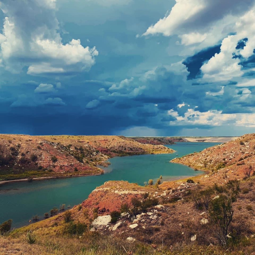 A storm coming in at Lover's Canyon. The sky is dark blue with dark clouds. The lake is greenish.